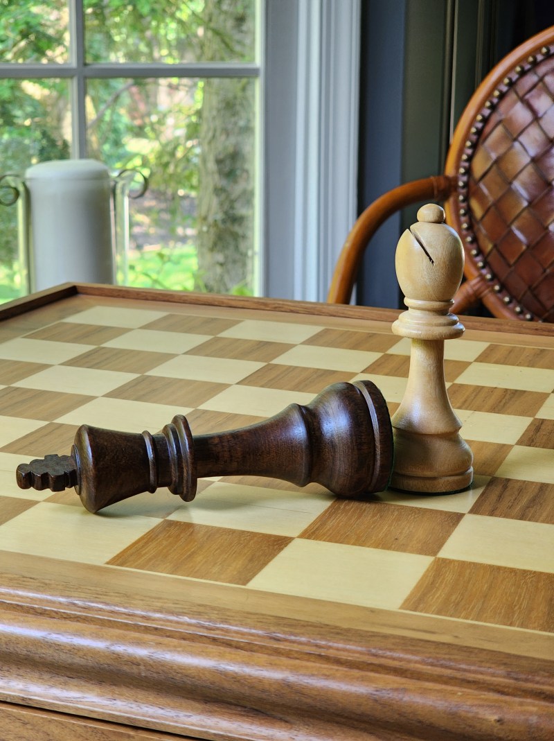A white bishop standing over a toppled black king on a chessboard
