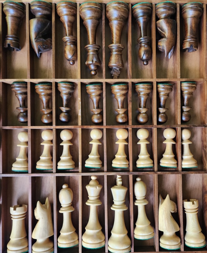 Chess pieces arranged in rows in a wooden box